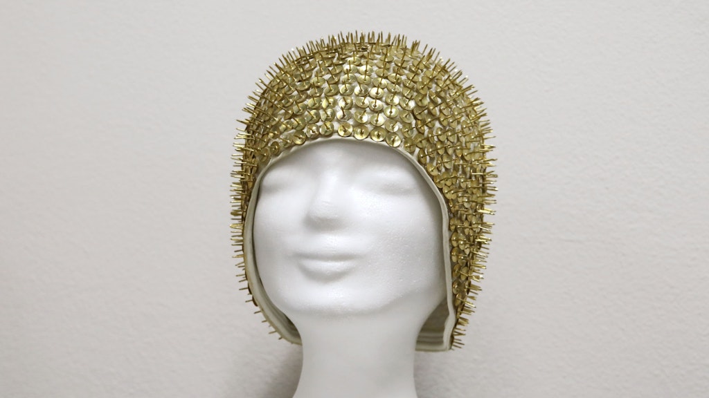 Außen stachelig. Mit goldenen Reißzwecken verzierte Badekappe.