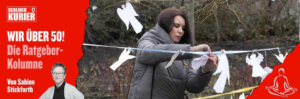 Eine Frau befestigt Papierfiguren in Form von Engeln an einem Band in der Nähe der Gedenkstätte der Zusammenstöße auf dem Maidan-Platz.