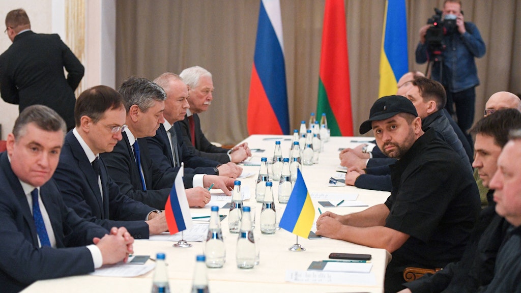 Die Delegationen sitzen sich gegenüber: Links mit Brille der russische Verhandlungsführer Wladimir Medinski, rechts mit Mütze sein ukrainischer Gegenpart David Arachamija.