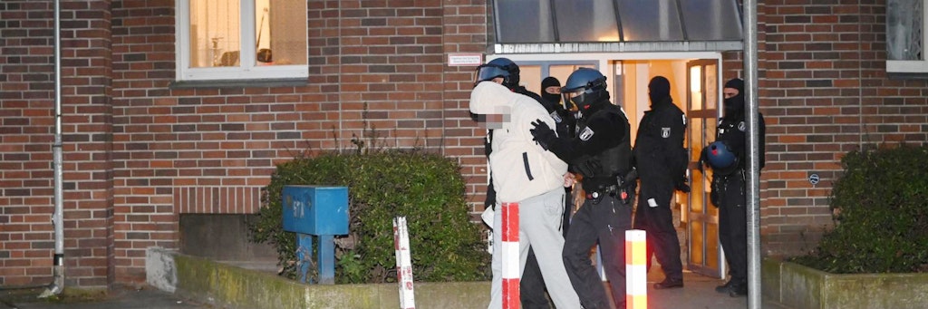 Schwerbewaffnete Polizisten führen einen Festgenommenen im Graefekiez ab.