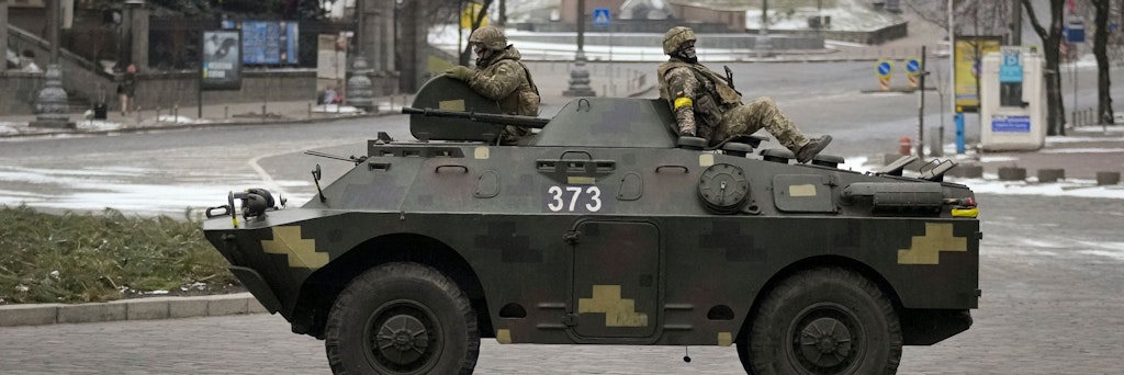 Ukrainische Soldaten fahren auf einem gepanzerten Mannschaftswagen einen verlassenen Boulevard in Kiew entlang.