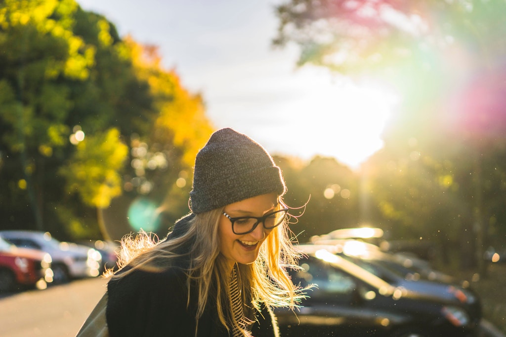 Eine junge Frau lacht in der Sonne. Das Wetter in den kommenden Tagen wird richtig schön.