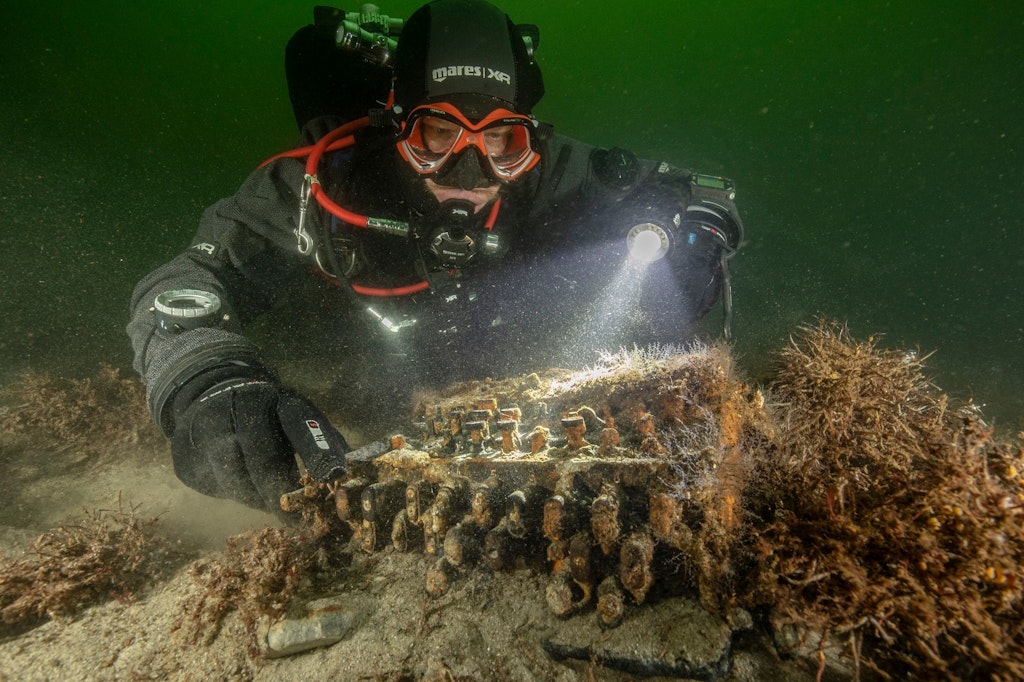 Forschungstaucher mit der Enigma-Chiffriermaschine, die in der Ostsee in einem Fischernetz hing.