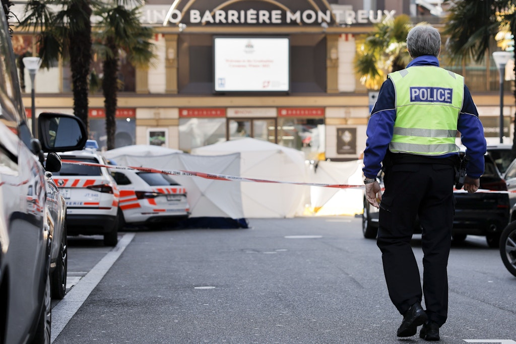 Ein Polizist geht zum abgesperrten Ort, an dem mehrere Menschen aus einer Wohnung in den Tod gesprungen sind.