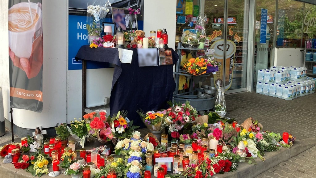 Blumen und Kerzen erinnern an einer Tankstelle in Idar-Oberstein an den jungen Kassierer.