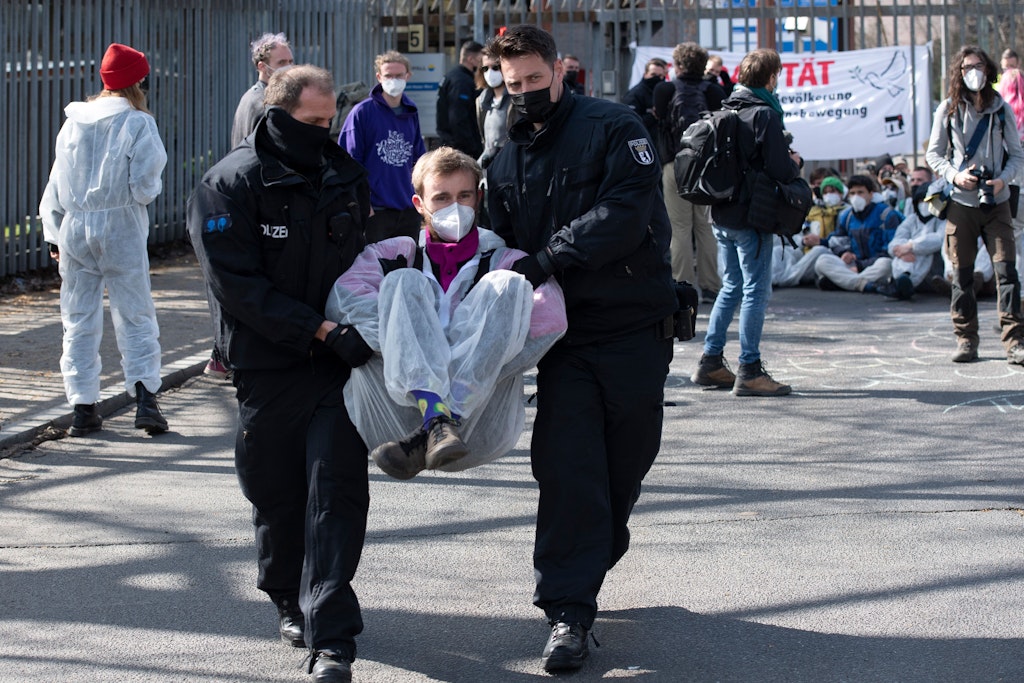 Polizisten tragen einen Demonstranten von Zufahrt zum Heizkraftwerk Reuter West.