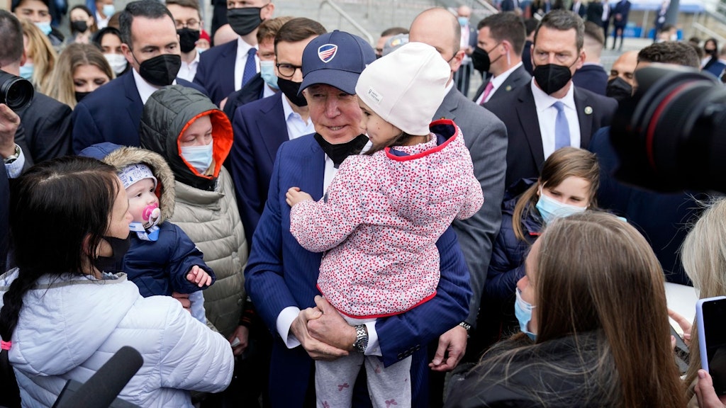 Joe Biden trifft bei seinem Besuch in Polen auf ukrainische Geflüchtete und nimmt ein Kind auf den Arm.