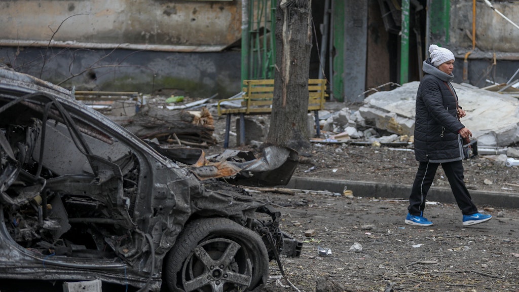 Eine Frau geht an den Trümmern eines Autos im Stadtteil Soltavka in Charkiw, Ukraine, vorbei.