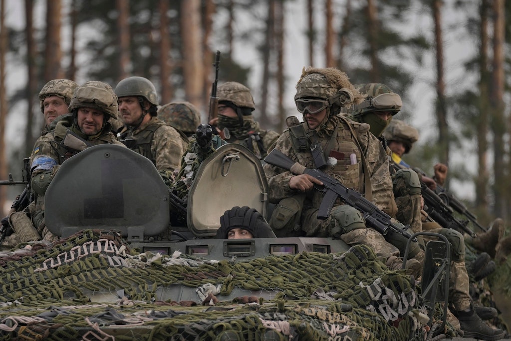 Ukrainische Soldaten sitzen auf einem Schützenpanzer während sie von russischen Soldaten aufgegebene Stellungen nahe Kiew durchfahren.