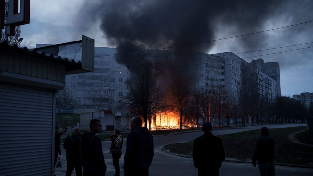Anwohner stehen vor ihren Wohnungen in Charkiw, während Geschäfte nach einem russischen Angriff brennen.