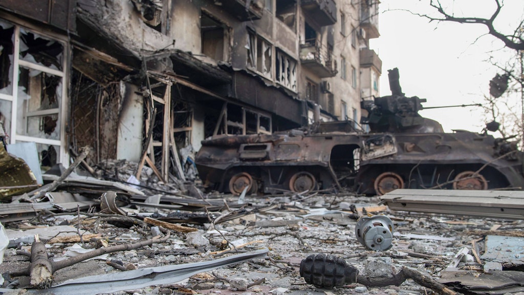 Ein zerstörter Schützenpanzer vor einem schwer beschädigten Haus in Mariupol.