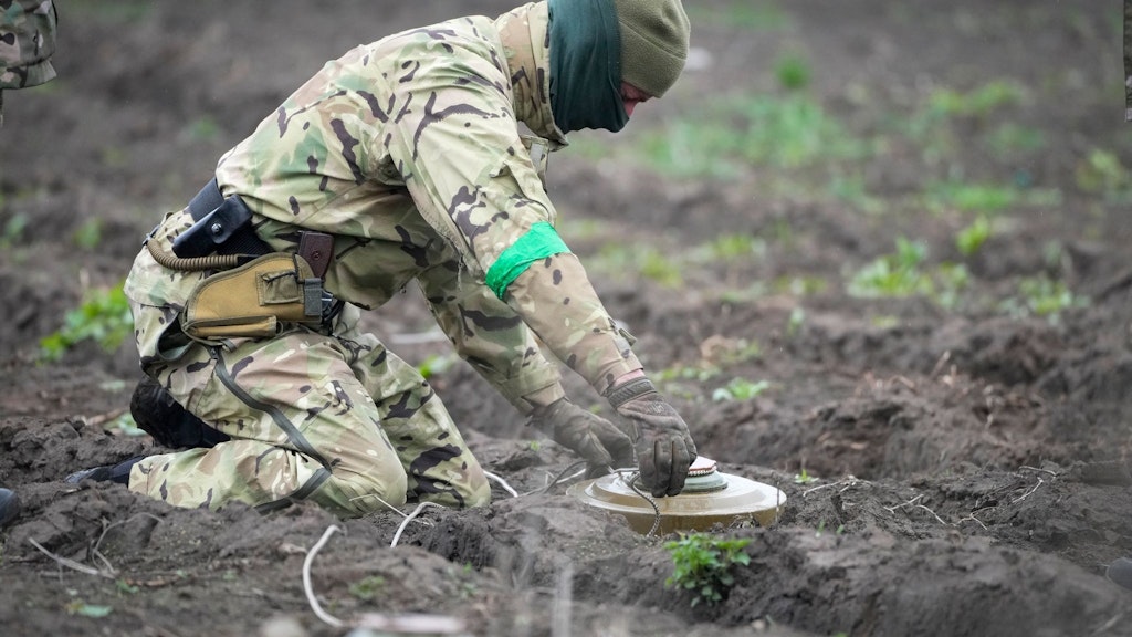 Ein militärischer Mitarbeiter des Innenministeriums entschärft auf einem Minenfeld nach den jüngsten Gefechten in Irpin eine Mine.