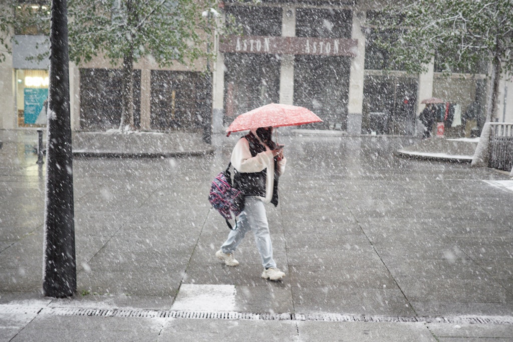 Eine Frau läuft bei dichtem Schneefall durch die spanische Stadt Pamplona.