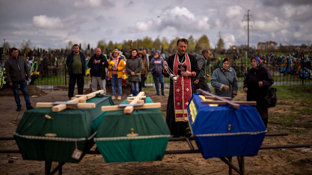 In Butscha segnet ein Priester segnet drei Verstorbene, die während der russischen Besatzung starben und aus provisorischen Gräbern in Butscha exhumiert wurden.