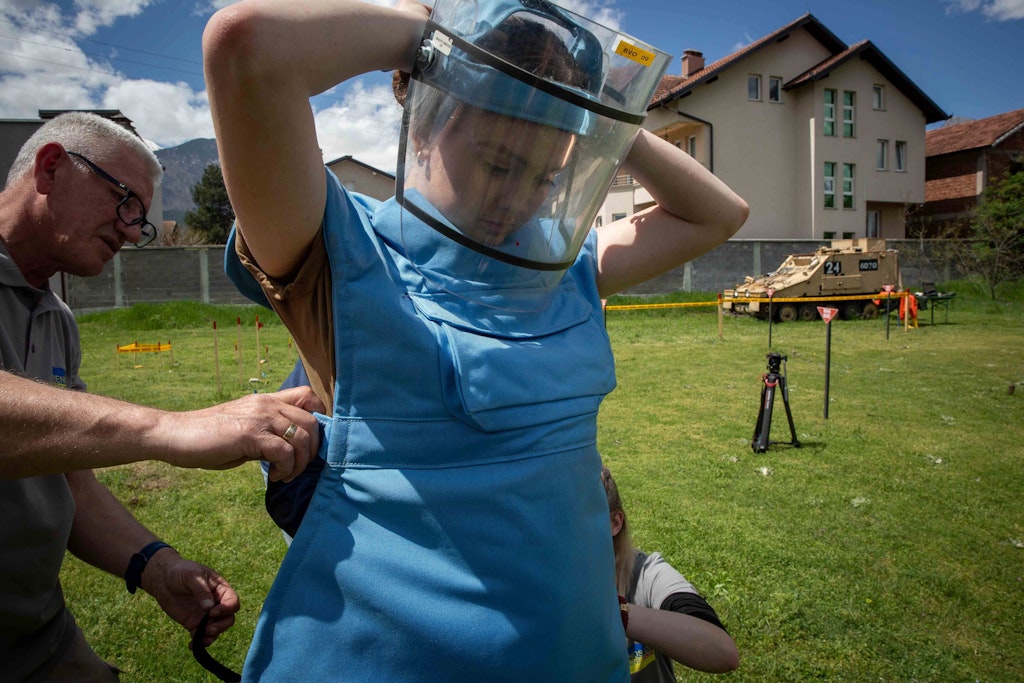 Anastasia Mintschukowa (r.) legt sich einen Schutzanzug und ein Visier an. Sie gehört zu einer Gruppe ukrainischer weiblicher Einsatzkräfte, die eine Spezialausbildung in der Kampfmittelbeseitigung und eine Vermessungsausbildung absolvieren.