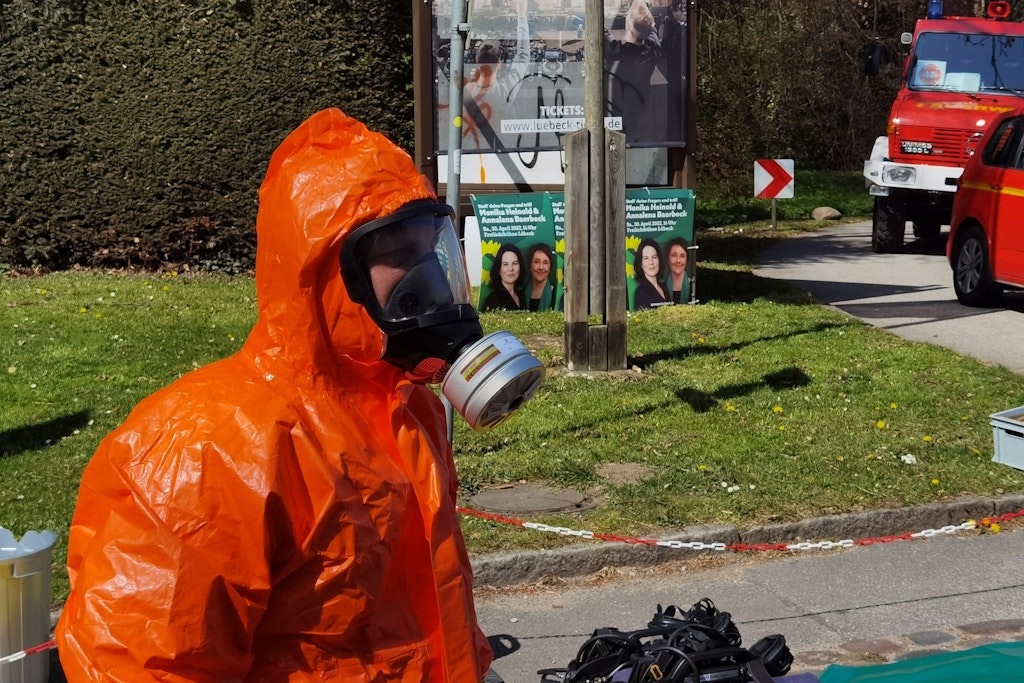 Ein Feuerwehrmann im ABC-Schutzanzug steht in der Nähe der Freilichtbühne in Lübeck, wo es einen Zwischenfall gegeben hat. Hier sollte auch Annalena Baerbock reden.