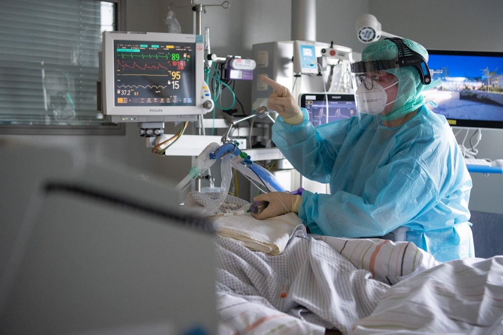 Eine Intensiv-Pflegerin versorgt einen schwer an Corona erkrankten Patienten auf der Intensivstation