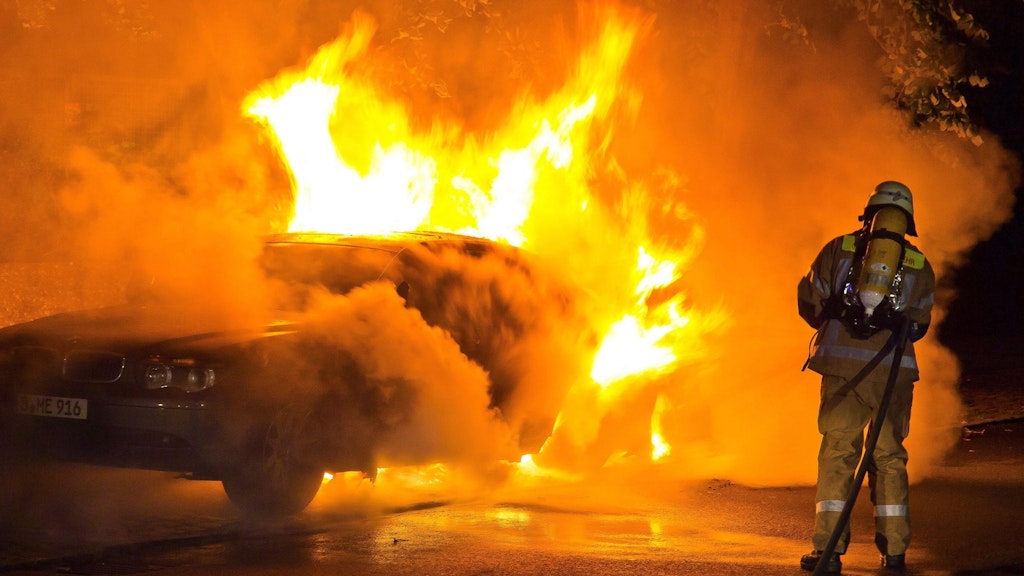 Ein Feuerwehrmann löscht ein von Hassbrennern in Brand gesetztes Auto in Berlin-Kreuzberg (Symbolfoto).