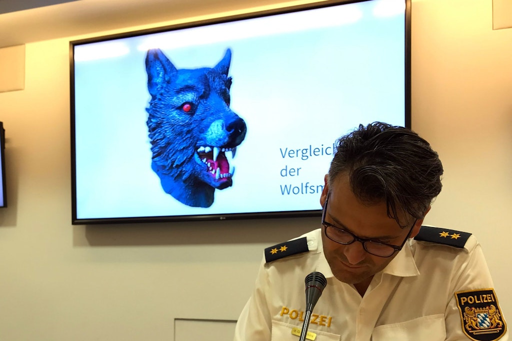 Marcus da Gloria Martins, Sprecher der Münchner Polizei, sitzt vor einem Bildschirm, auf dem die Polizei ein Vergleichsbild einer Wolfsmaske präsentiert. Mit einer solchen Maske hatte sich der Täter der Elfjährigen genähert und sie vergewaltigt.