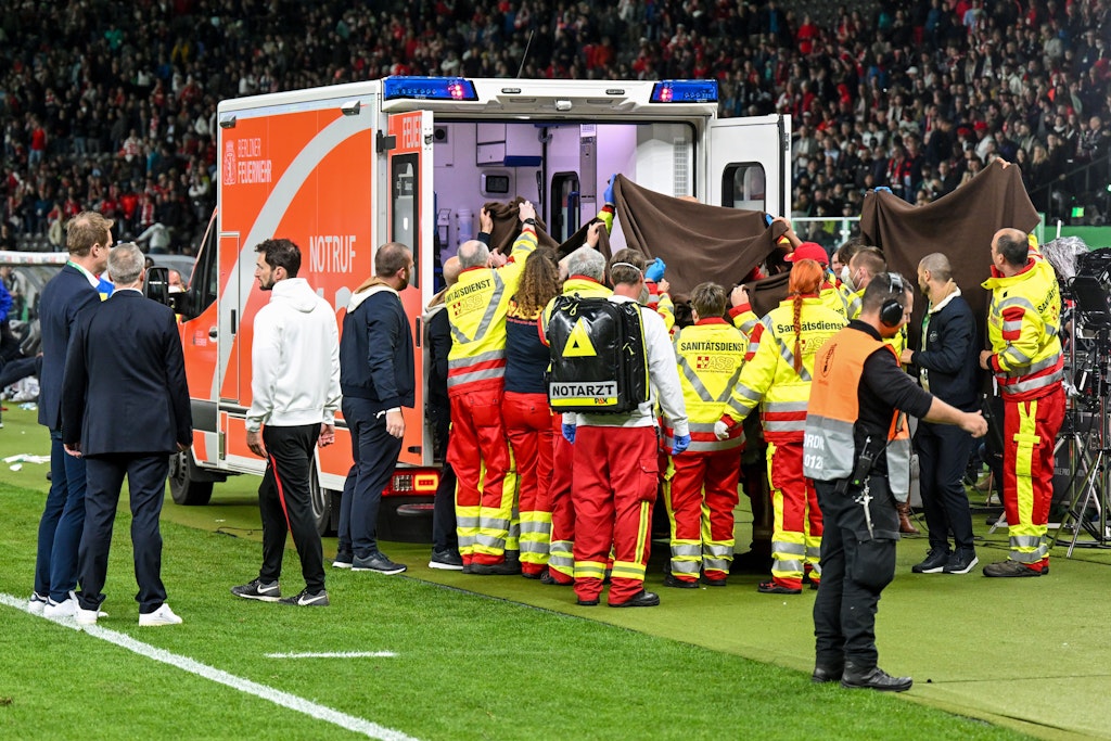 Rettungssanitäter bringen den Fotografen in den Rettungswagen.