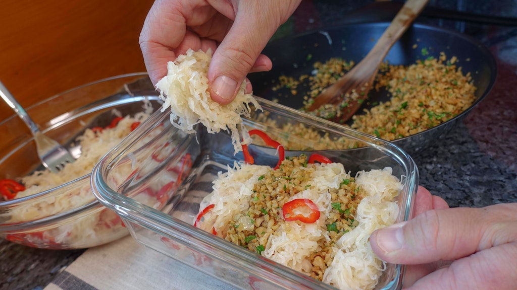 Für den Auflauf werden Sauerkraut und Hackfleisch abwechselnd in die Form geschichtet.
