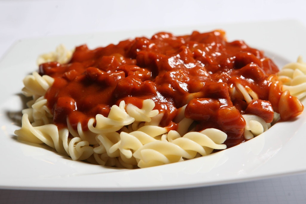 Spirelli mit Tomatensoße und Jagdwurst gab es bei der Schulspeisung in der DDR immer wieder – in diesem Rezept erfahren Sie, wie Sie das Gericht selbst zaubern.