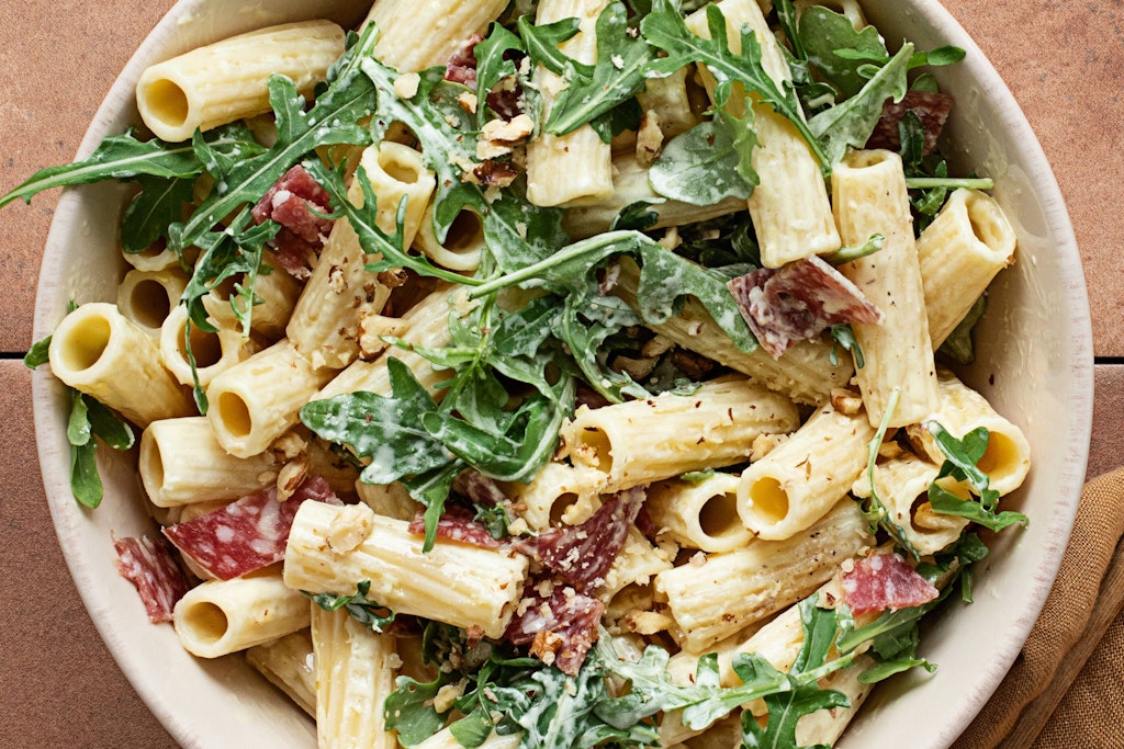 Dieser Nudelsalat mit Salami, Rucola und Nüssen ist einfach köstlich - das Rezept bringt Abwechslung aufs Grill-Buffet.