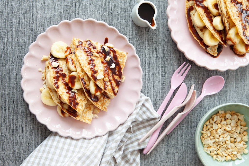 Eierkuchen sind ein echter Genuss und können nach dem Grundrezept zubereitet und dann beliebig serviert werden - hier mit Schokoladensoße, Bananen und Nüssen.