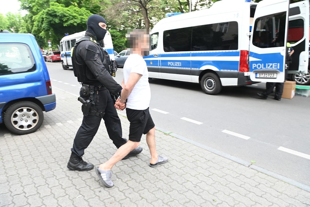 Ein Mann in Hausschuhen wird gefesselt in der Bülowstraße abgeführt.