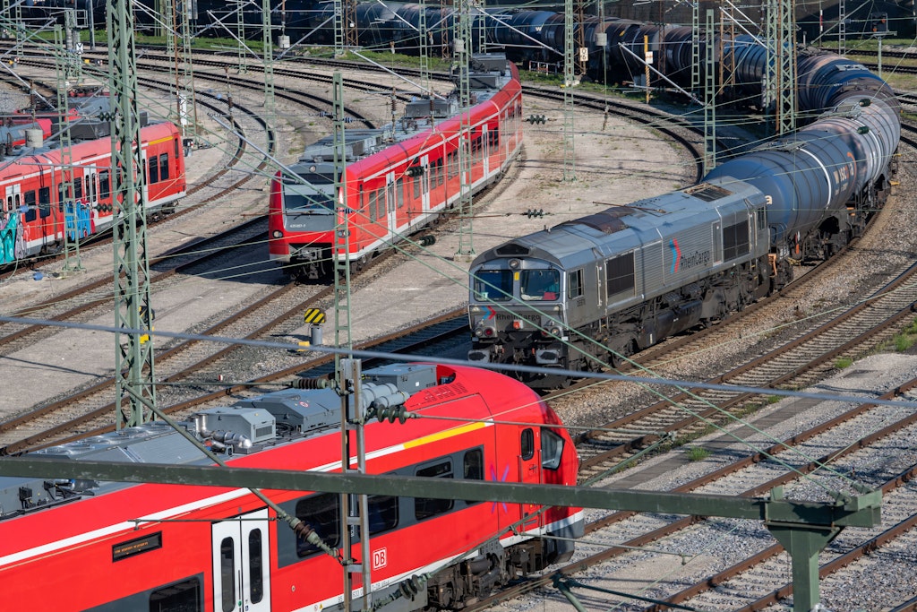 Ein Güterzug rollt an abgestellten Zügen der Deutschen Bahn vorbei.