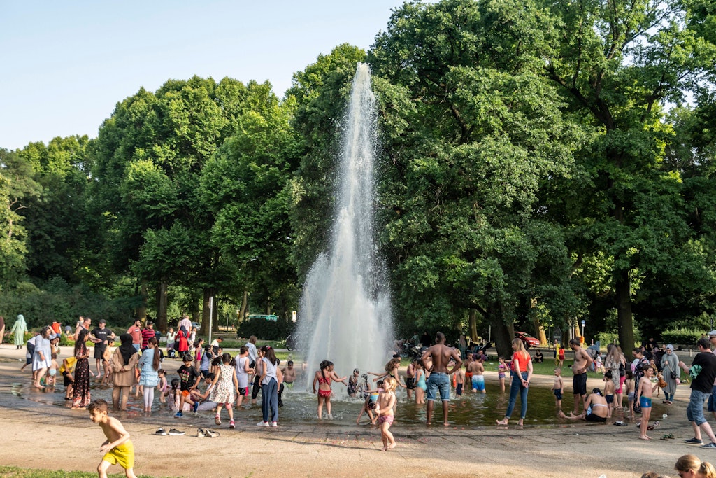 Familien am Springbrunnen im Treptower Park: Die Kinder kühlen sich an der Plansche ab, doch für Ältere werden die Temperaturen zum lebensbedrohlichen Risiko.