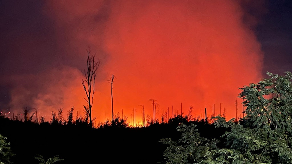 Rot erleuchtet ist der Nachthimmel durch das Feuer eines Waldbrands in der Nähe der brandenburgischen Kleinstadt Treuenbrietzen. Foto: Christian Guttmann/dpa
