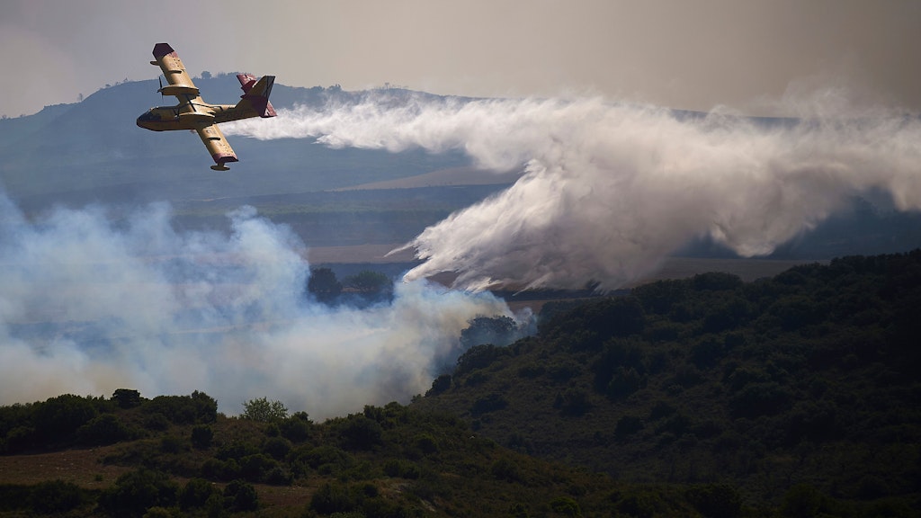 Spanien, San Martin De Unx: Ein Löschflugzeug wirft ein Feuerschutzmittel auf ein brennendes Gebiet ab. Die spanische Feuerwehr kämpft in mehreren Teilen des Landes, die von einer für diese Jahreszeit ungewöhnlichen Hitzewelle betroffen sind, um die Eindämmung von Waldbränden.