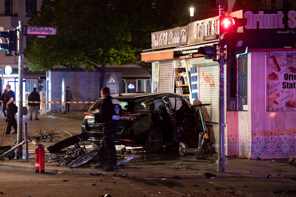 Ein zerstörter Pkw steht auf der Berliner Müllerstraße in einem Imbiss.