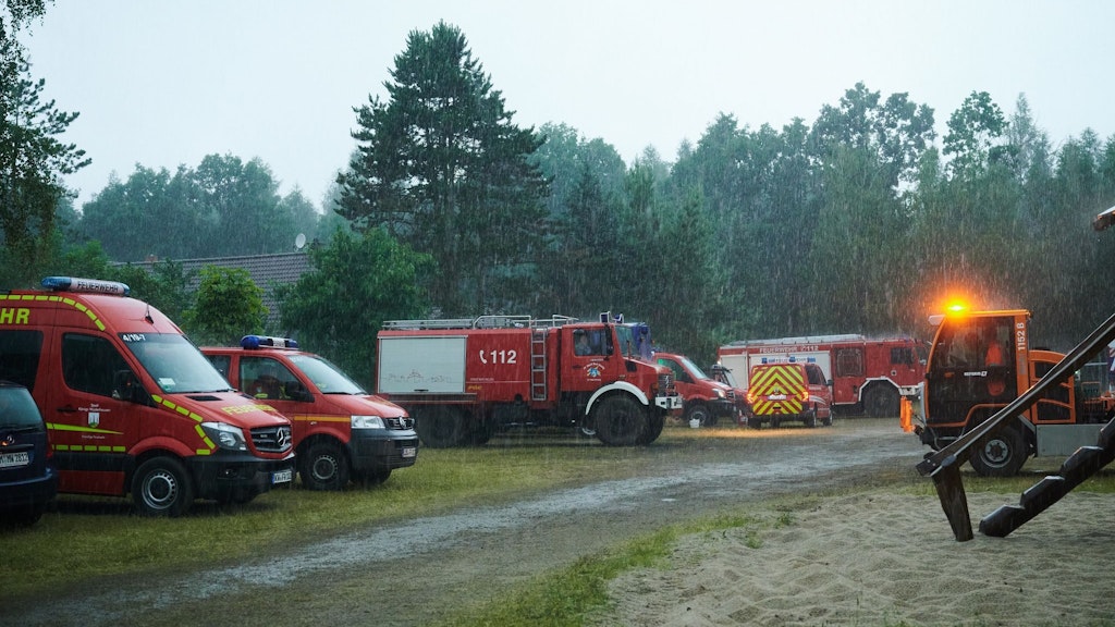 Erleichterung: Starker Regen prasselt auf Rettungsfahrzeuge von Feuerwehr und THW nahe Treuenbrietzen.