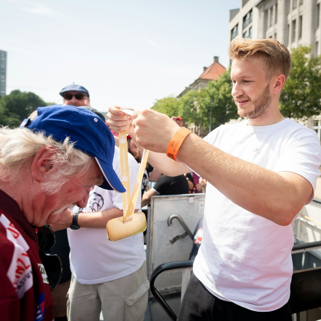 Eisbären-Verteidiger Eric Mik hängt Edelfan Manfred Schmee die Meistermedaille um.