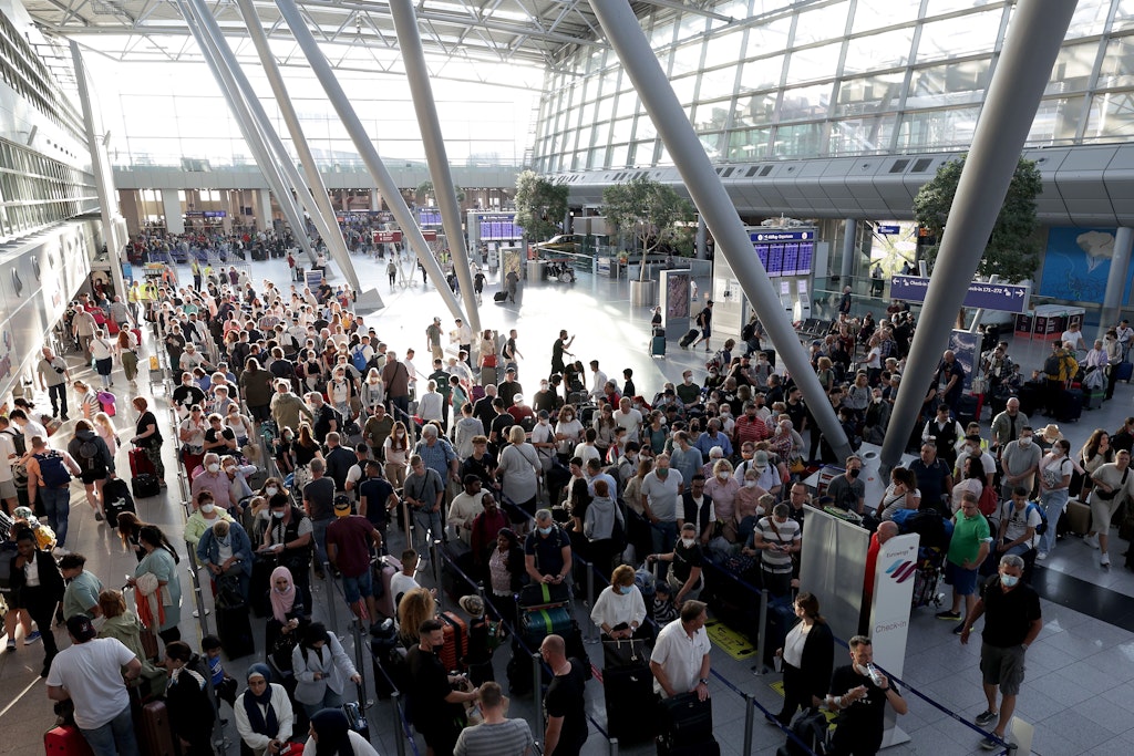Passagiere drängeln sich in langen Schlangen vor den Schaltern im Flughafen Düsseldorf und warten auf die Abfertigung.
