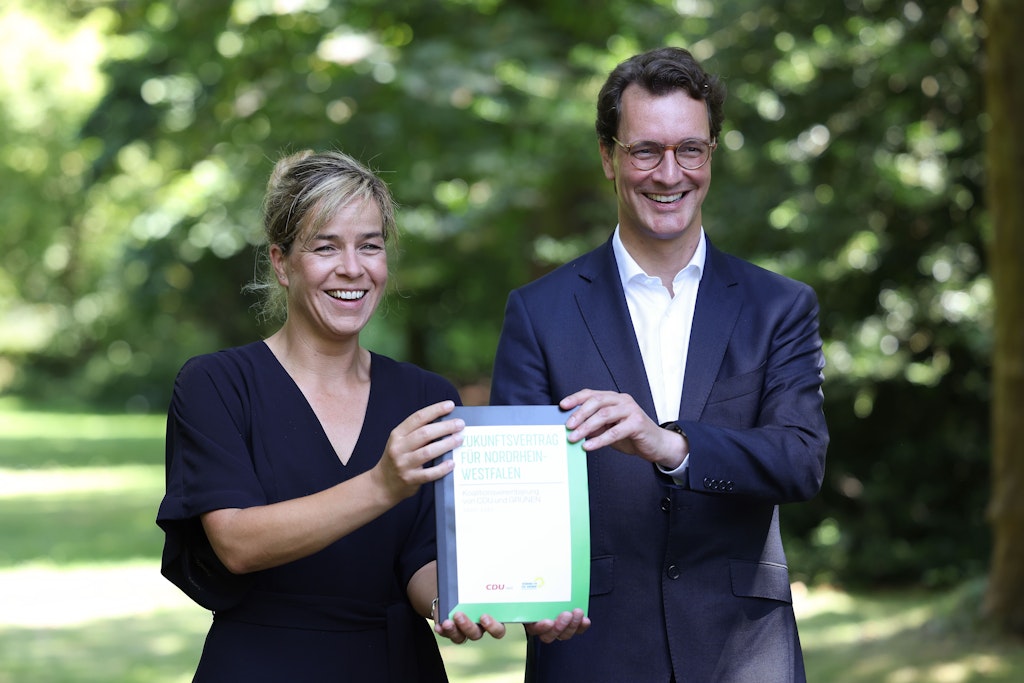 Ministerpräsident Hendrik Wüst (CDU) und die NRW-Grünen-Vorsitzende Mona Neubaur mit dem schwarz-grünen Koalitionsvertrag für ihre gemeinsame Regierung.