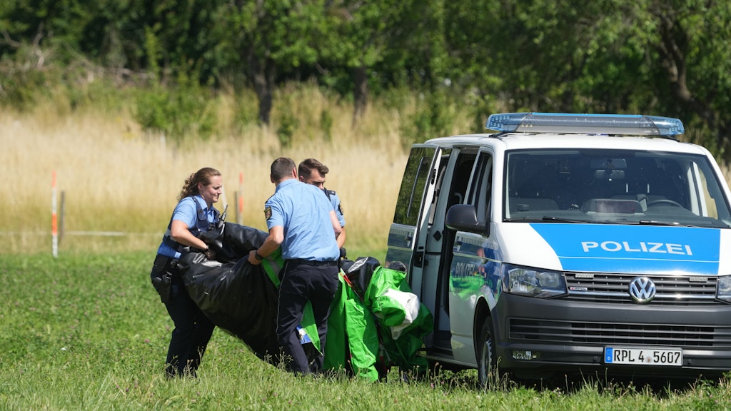 Polizeibeamte transportieren in Gondershausen die Hülle einer Hüpfburg, die zuvor durch eine Windböe in die Luft geschleudert wurde.