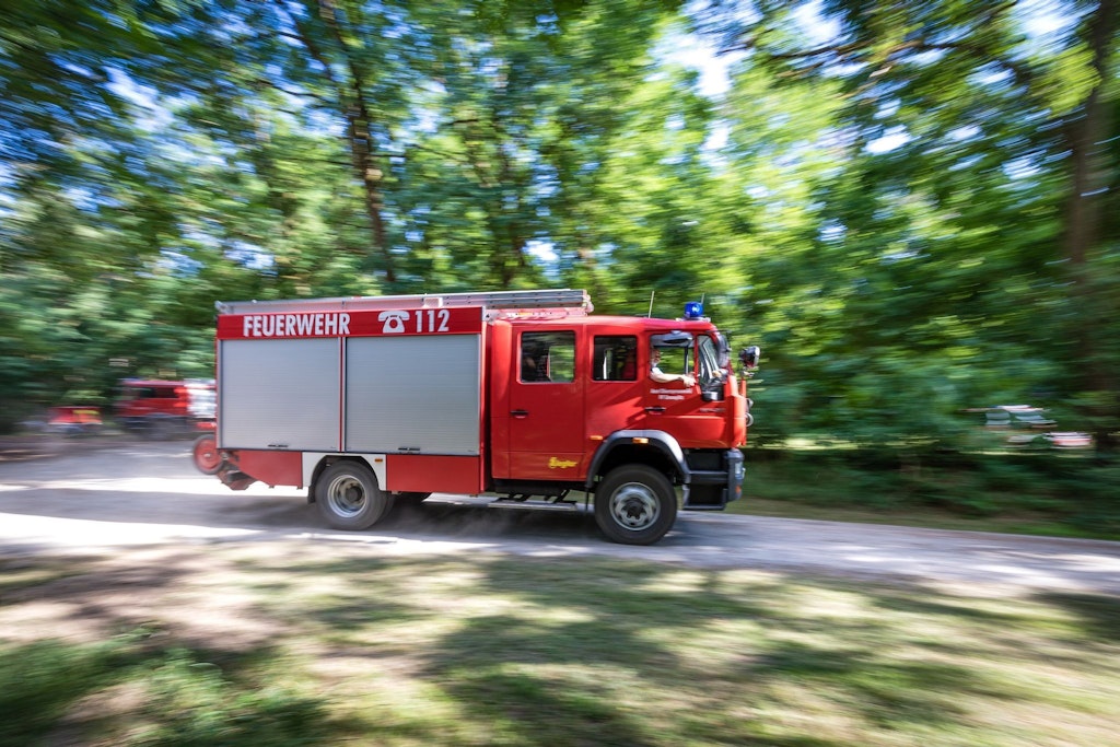 Ein Fahrzeug der Feuerwehr rast in der Nähe des Einsatzortes durch den Wald.