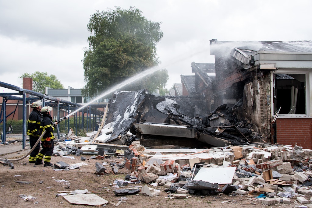 Feuerwehrleute löschen Trümmer eines Gebäudes der Stadtteilschule Finkenwerder. An der Schule hat es in der vergangenen Nacht einem Großbrand gegeben, Menschen wurden dabei nicht verletzt.
