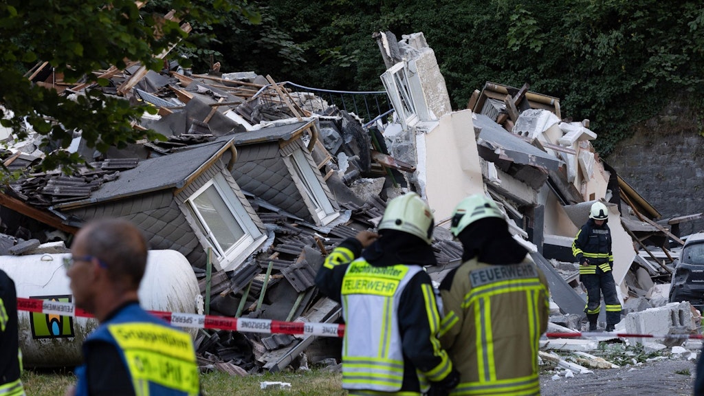 Rettungskräfte stehen vor den Trümmern des explodierten Hauses