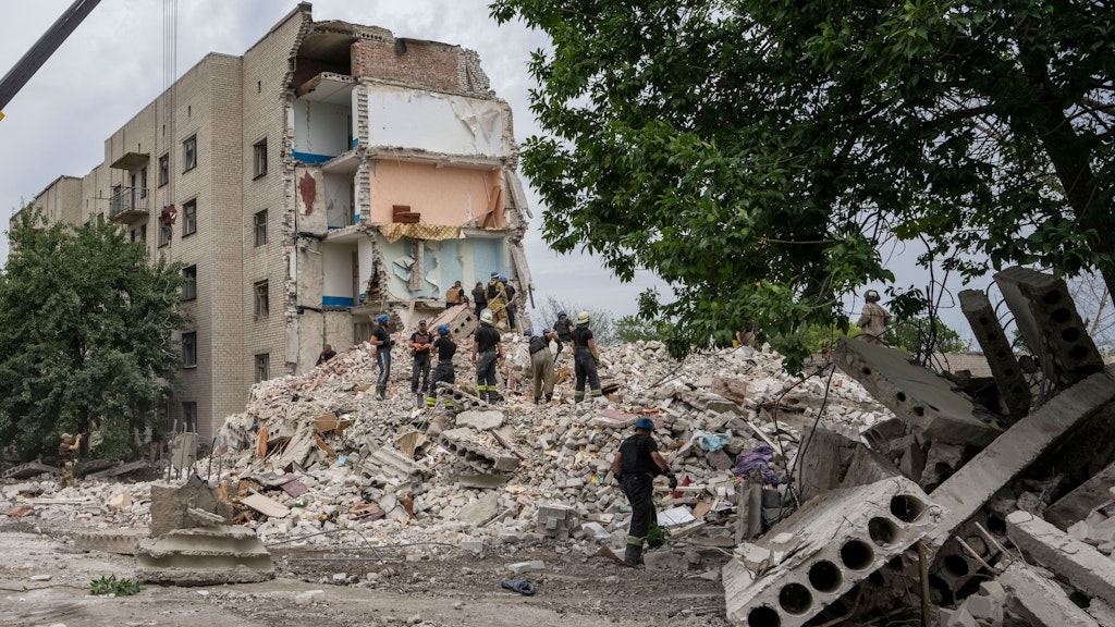 Rettungskräfte stehen auf den Trümmern eines Wohnblocks in Tschassiw Jar, nachdem eine russische Rakete eingeschlagen ist und mehrere Menschen getötet und verschüttet wurden.
