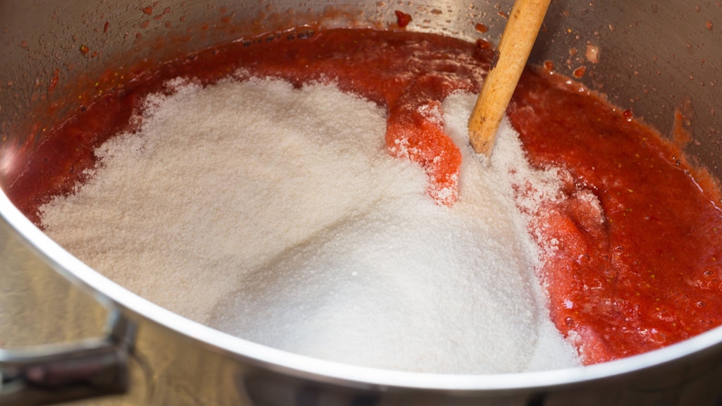 Aus Zucker und Erdbeeren wird im Kochtopf Marmelade.