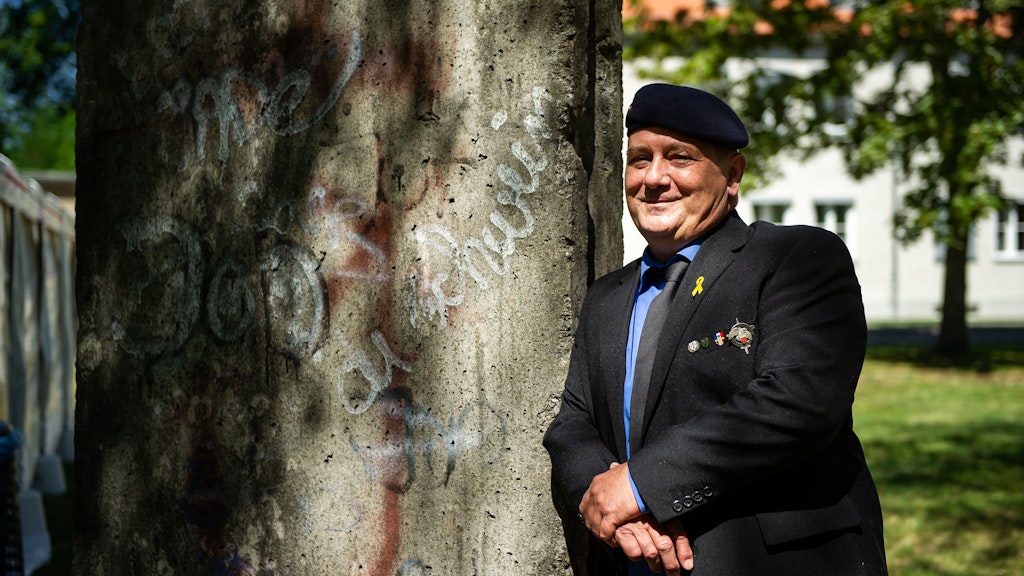Bernard Leraille lehnt an einem Mauer-Segment in der Julius-Leber-Kaserne. Die Mauer hat sich in sein Gedächtnis eingebrannt, als er in Berlin seinen Militärdienst ableistete und hier blieb.