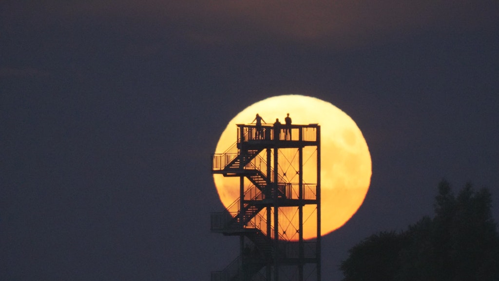 Niedersachsen, Syke: Schaulustige beobachten vom Aussichtsturm auf dem Hohen Berg den Mondaufgang.