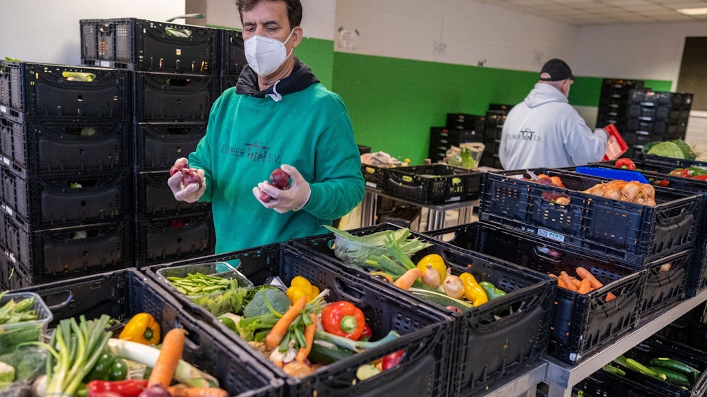 Mitarbeiter der Berliner Tafel packen Lebensmittel in Kisten.