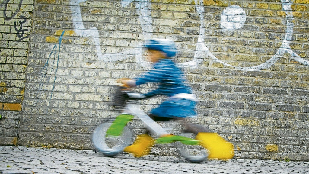 Kind auf einem Laufrad. Bis zum Alter von acht Jahren müssen Kinder auf dem Gehweg fahren.