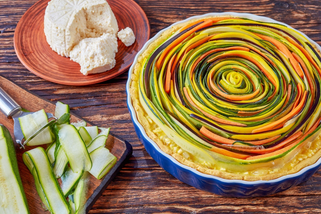 Nicht nur sehr lecker, auch was fürs Auge! Bei dieser Quiche werden Zucchini und Möhren in dünnen Streifen spiralförmig auf den Teigboden gesetzt.