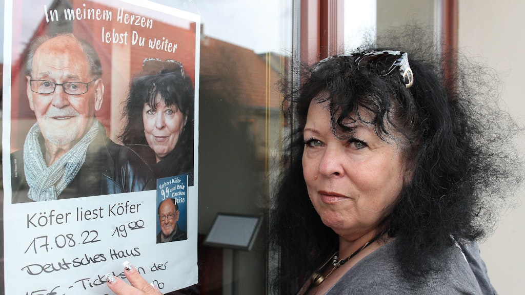 Heike Köfer steht am Deutschen Haus in Beelitz, wo bereits für ihren Auftritt „Köfer liest Köfer“ geworben wird.